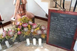 On the ground floor of Bergsig, the menu of the day is available as the restaurant is on the second floor. The old copper brandy still is in the background and cut Proteas in full bloom add a splash of color.