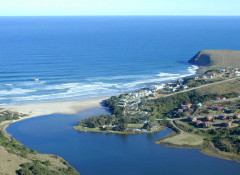 The Morgan Bay Hotel is the large white building with a flat roof in the middle of the other white buildings on the beach. The placid blue water below is the Kei River Mouth. The hotel is nestled on a mile of beach and cliffs.